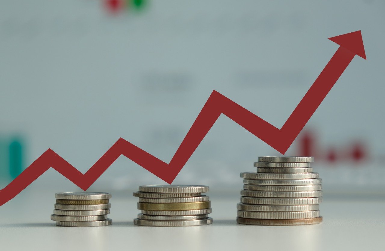 Image shows increasingly taller stacks of coins with a graph going up and up to demonstrate increasing costs.